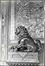Cloisonne lion on r. of stable entrance with paw over cub