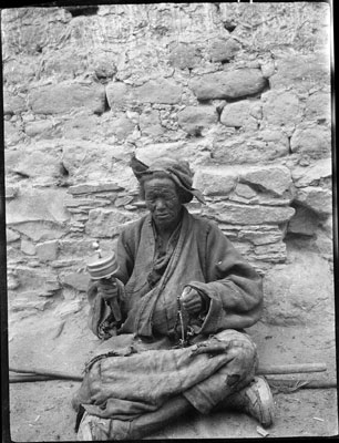 Old woman spinning prayer wheel, Gyantse Bazaar