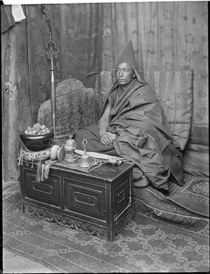 A Priest of the Yellow Hat Sect. In front of him from right to left are his Dor-je, bell, cup made from a skull, and drum made from two skulls