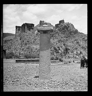 Pillar of Khri Srong-lde-brtsan at &lsquo;Phyong-rgyas with lion and dragon carvings. &lsquo;Phyong-rgyas Rdzong in the background.