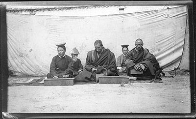 Monks and lay officials seated in front of a wall