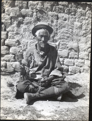 Beggar in Lhasa with prayer wheel and rosary