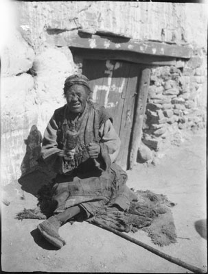 Blind woman beggar with prayer wheel