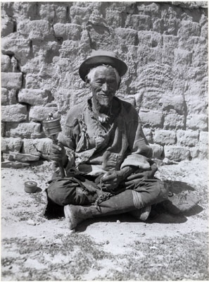 Beggar in Lhasa with prayer wheel and rosary