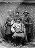 Wealthy merchant of eastern Tibet with servants. He wears a double necklace of corals and onyx. Scabbard of servant on right holds three corals, as is usual in eastern Tibet